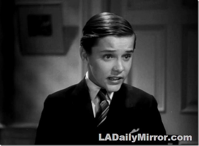 Boy in suit coat and tie, hair neatly combed. 