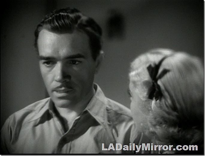 Mystery man wearing shirt with open collar. He has dark hair and a slight mustache. Back of the Head Woman has light hair tied with a bow. 