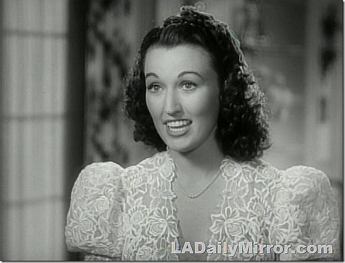 Woman in elegant dress, wavy hair with a slight widow's peak. 