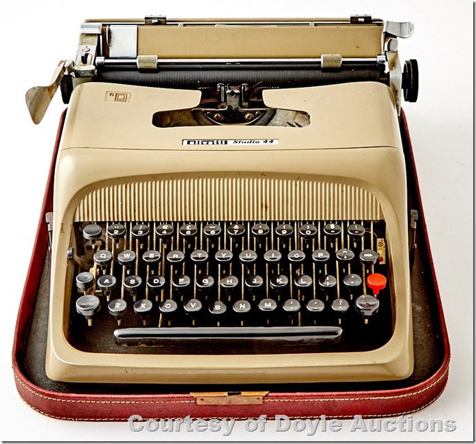 A beige typewriter with black keys in the bottom of a red travel case. A beige typewriter with black keys in the bottom of a red travel case.