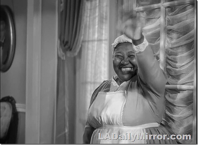 Woman in maid's outfit, waving.