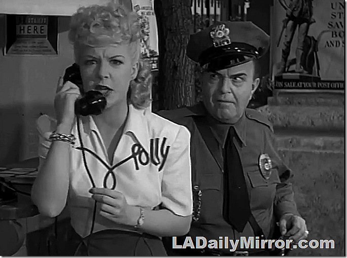 Woman talks on telephone while security guard watches. 