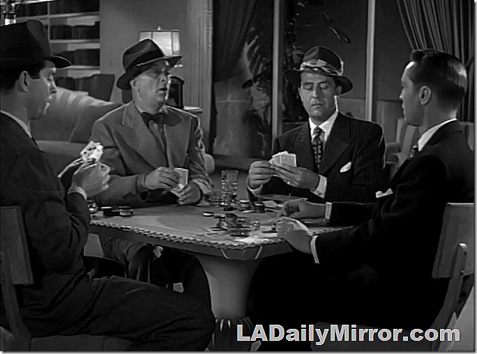Four men playing cards. Three are wearing hats. 