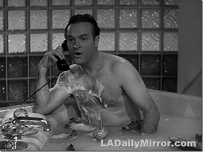 Man in bathtub, talking on the phone. 