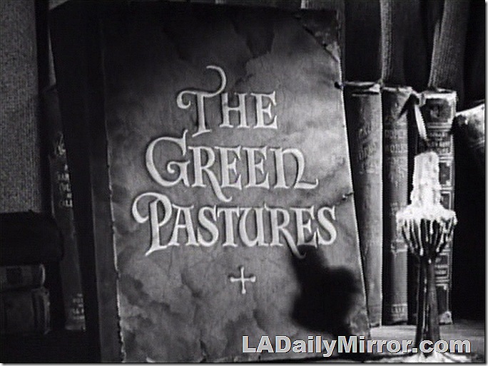 Main Title: Lettering on the cover of a book next to a candle burning in a candlestick. 