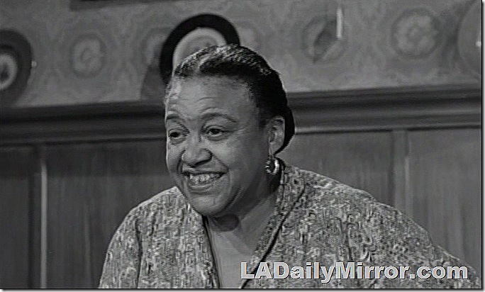 Older woman, hair pulled back, wearing earrings. 