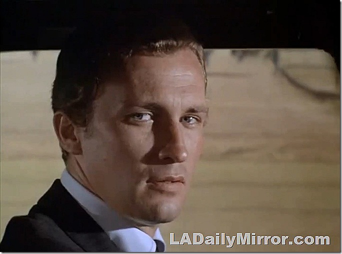 Man wearing coat, white shirt and tie. He is looking directly at the camera. 