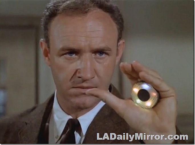 Man in coat and tie holding disc with five small lights