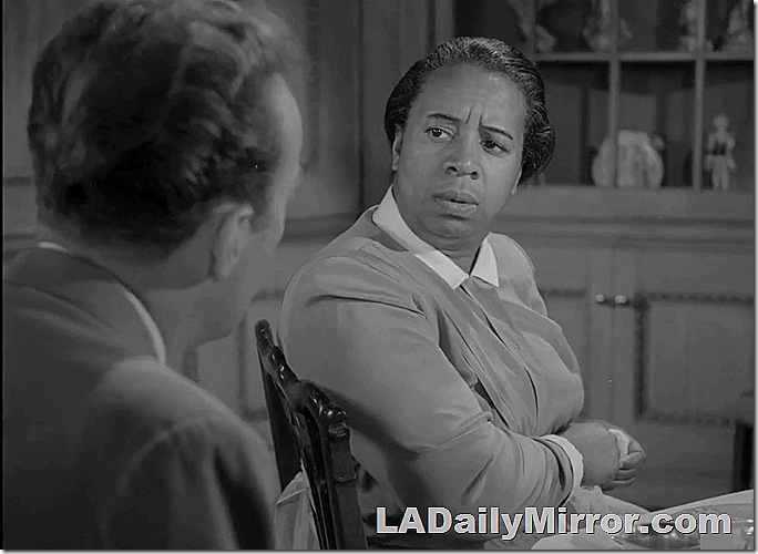 Woman turned halfway in chair to look at man who has his back to the camera. 