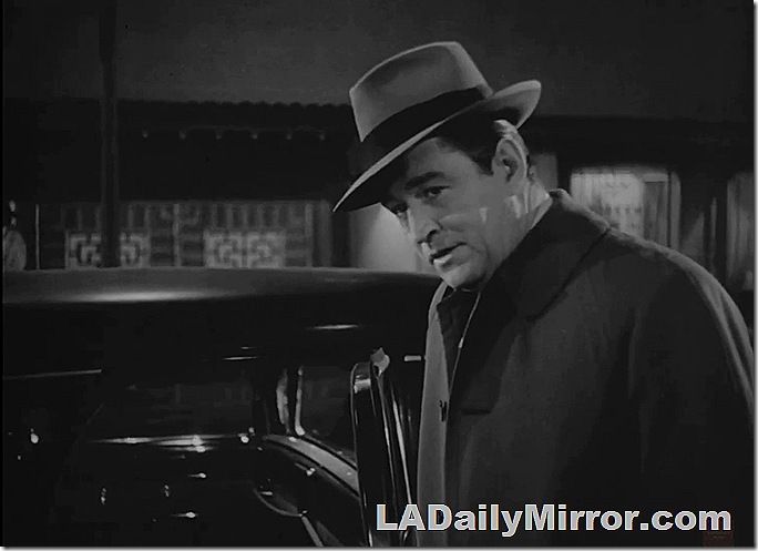 Man in hat and coat standing next to car. 