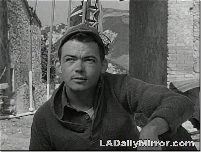 Man wearing shirt, .sweater and knit cap. 