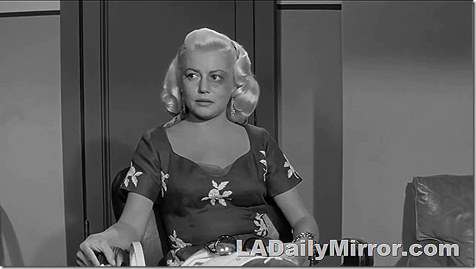 Platinum blond in short-sleeve dress and a black eye. 