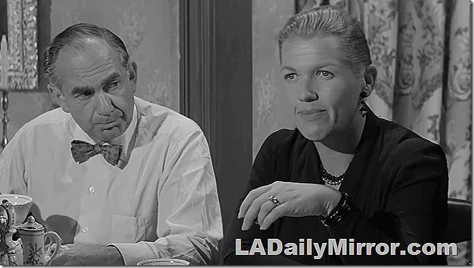 Man in shirt and bow tie sitting next to woman with short hair. 