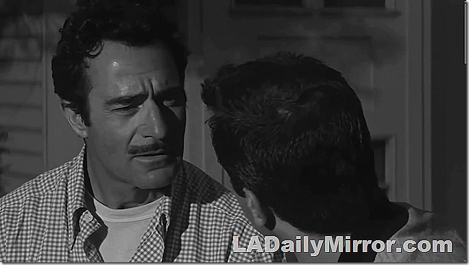 Man with mustache and checked shirt looking at Back of the Head Guy. 