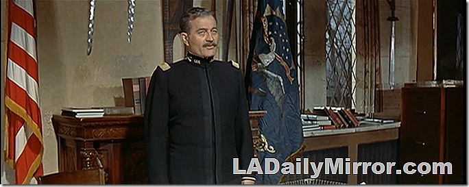 Man in uniform with flags in the background. 