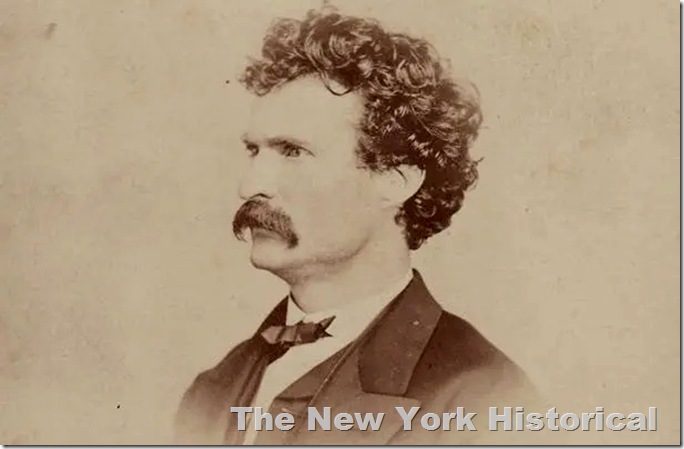 Mark Twain as a younger man, bushy hair and mustache in coat with string tie. 