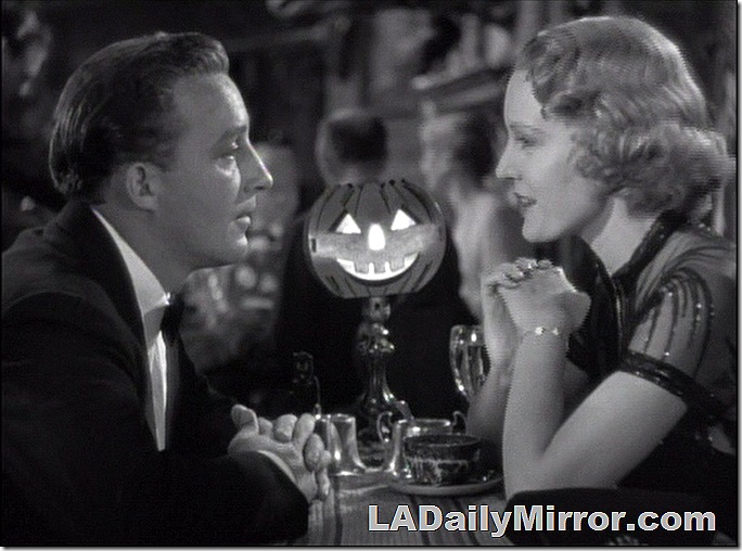 Man and woman facing each other at a table in a nightclub. 