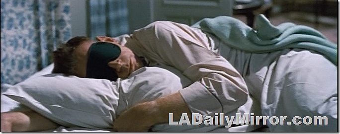 Man in bed wearing a sleep mask. 