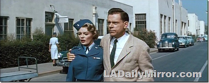 Woman in military uniform with man in coat and tie. 