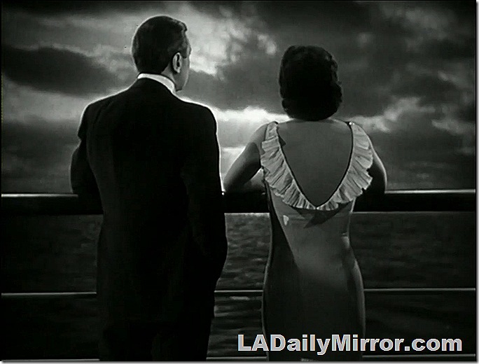 View of the ocean as seen by a man and a woman standing at the railing of an ocean liner. 