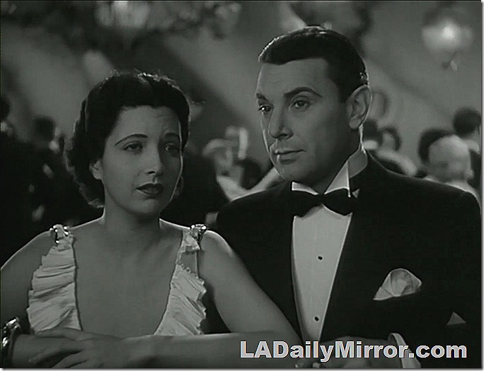 Elegantly dressed man and lady at the rail of an ocean liner. 