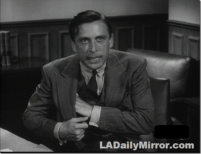 Man in double-breasted suit reaching into pocket.