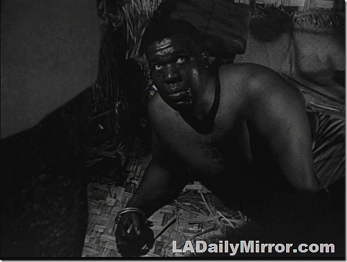 Man lying on floor, looking up at camera. 
