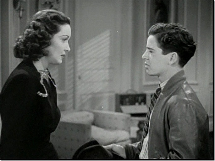 Woman in elegant dress talking to youth in leather jacket. 