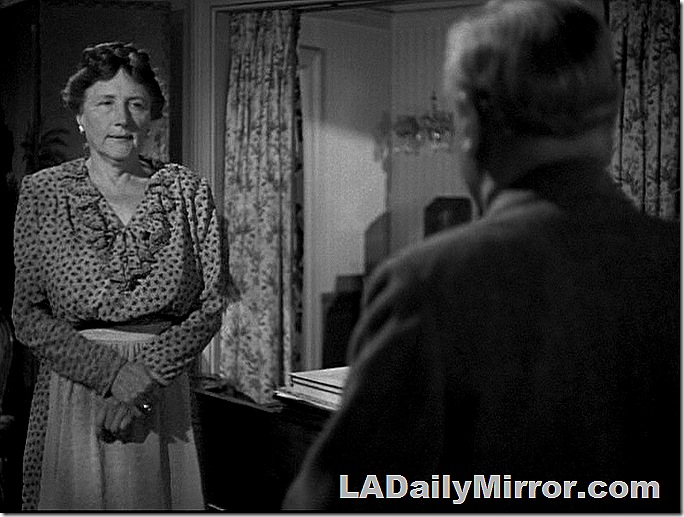 Woman with her hair up, wearing an apron, talking to man with back to camera. Woman with her hair up, wearing an apron, talking to man with back to camera.