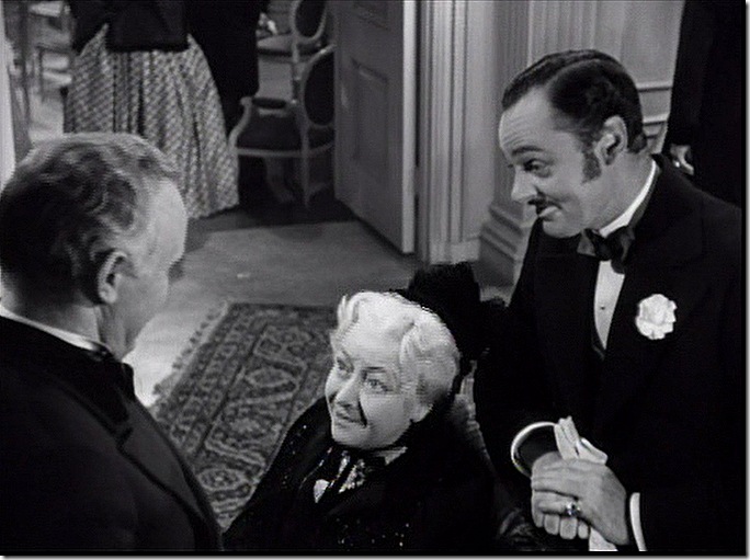 Older woman, seated. Man to the right is smiling, to the left is Back of the Head Guy. Older woman, seated. Man to the right is smiling, to the left is Back of the Head Guy.