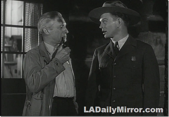 Man smoking a pipe talking to a man in a uniform 
