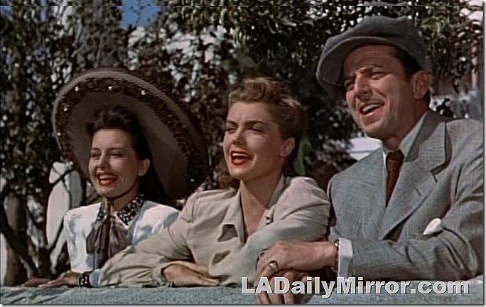 Two women and a man, all smiling. One woman is wearing a sombrero, the other is not. The man wears a newsboy cap. 