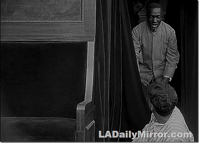 Man looking down at mystery fellow on the floor looking up. 