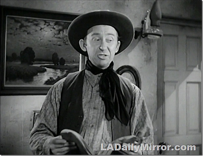 Man in cowboy hat, bandana and vest. 