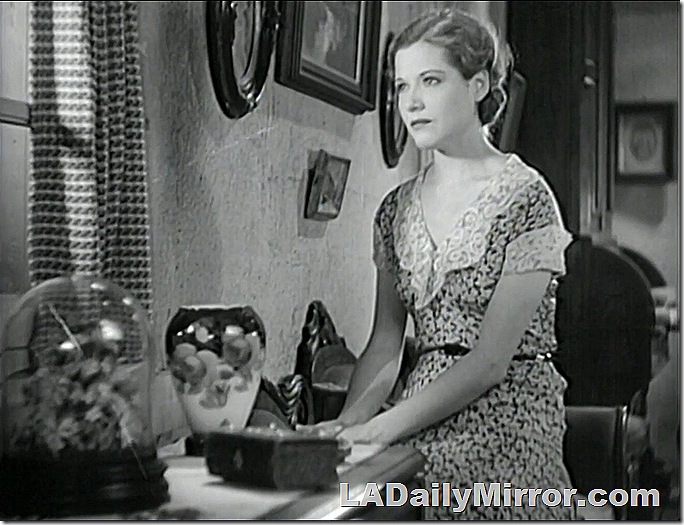 Woman in dress with lace collar looking out a window. 