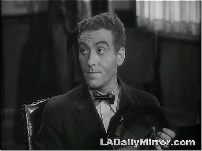 Man wearing bow tie, sitting in chair. 