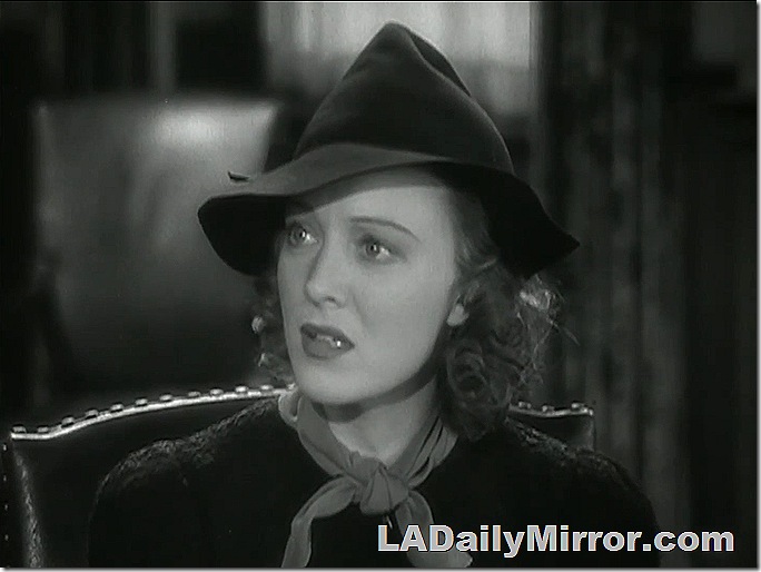 Woman wearing hat, sitting in chair. 