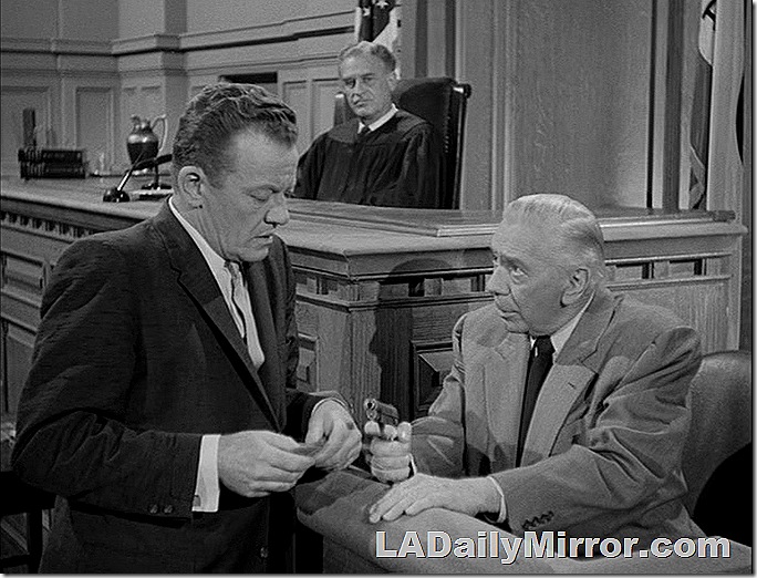 Two mysterious men looking at a pistol. A third man views the proceedings. 