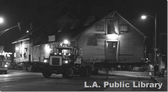 The Lasky barn on a flatbed trailer being moved by a truck. 