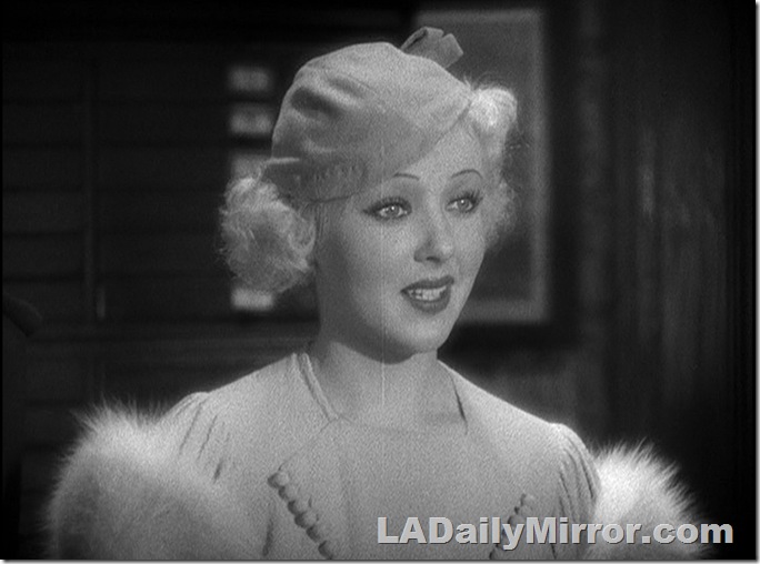 Blond woman wearing a hat and a dress trimmed with fur 