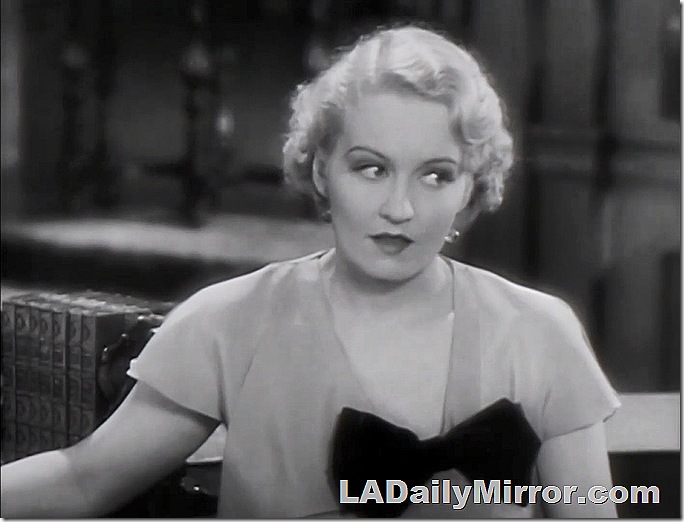 Woman with short blond hair, wear a dress with a large bow. 