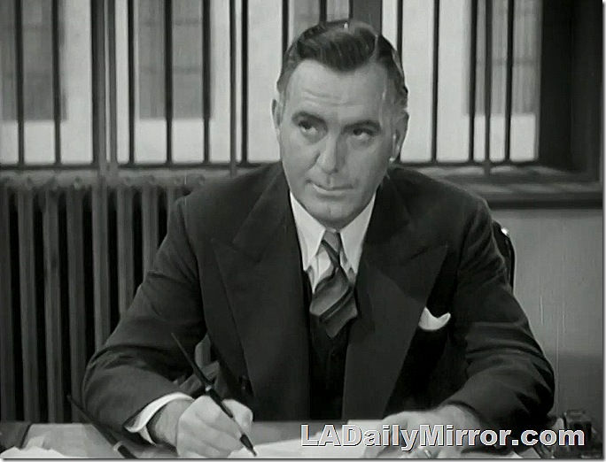 Man in three-piece suit a tie sitting at a desk. 