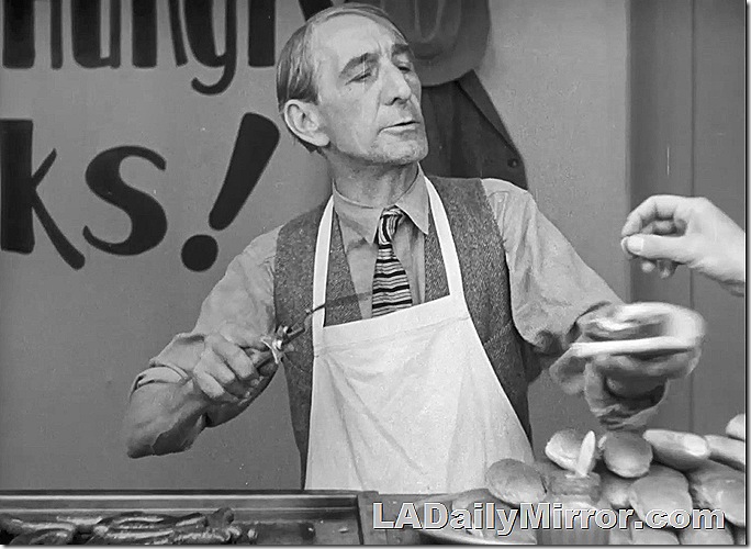 Man in apron selling hotdogs. Man in apron selling hotdogs.