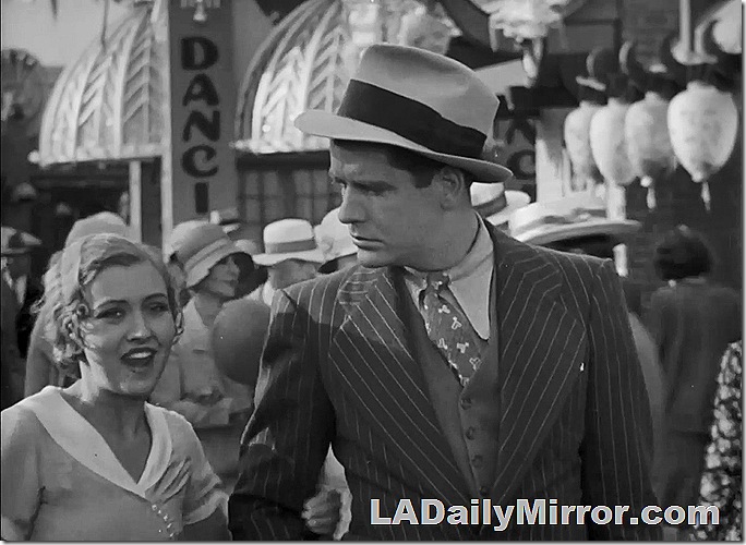 Man and woman. He wears a pinstripe suit and hat. She has short hair and wears a dress. Man and woman. He wears a pinstripe suit and hat. She has short hair and wears a dress.