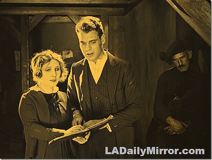 Man and woman holding a book. He wears a pinstripe suit, she wears a dress and a sweater. Man and woman holding a book. He wears a pinstripe suit, she wears a dress and a sweater.