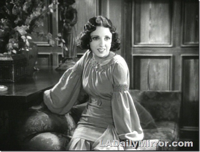 Woman in dress, sitting on the arm of a couch. Woman in dress, sitting on the arm of a couch.