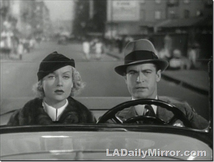 Fashionably dressed woman and man in hat a suit driving a roadster. 