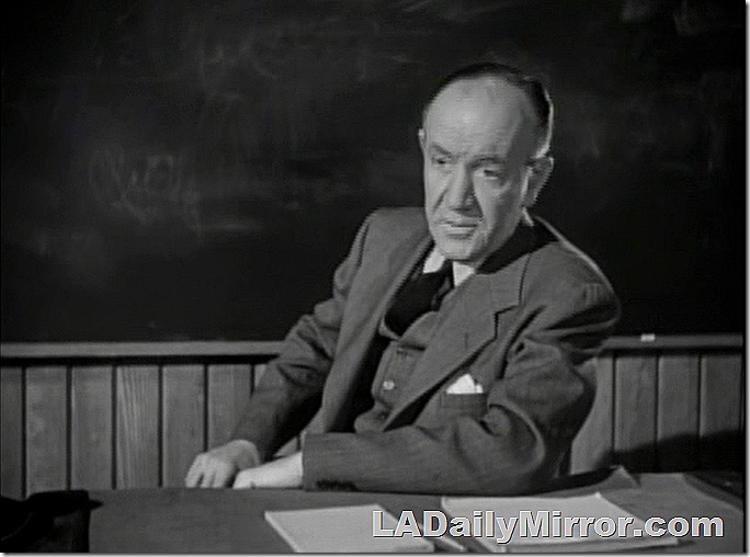 Balding man in three-piece suit and tie sitting at desk. 