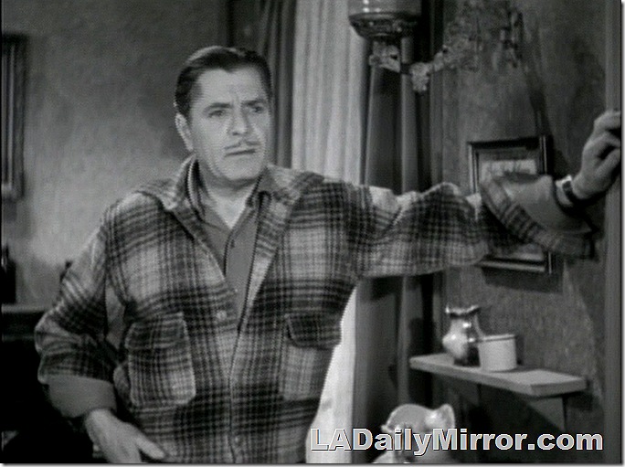 Man with mustache wearing flannel jacket, leaning against a wall. Man with mustache wearing flannel jacket, leaning against a wall.