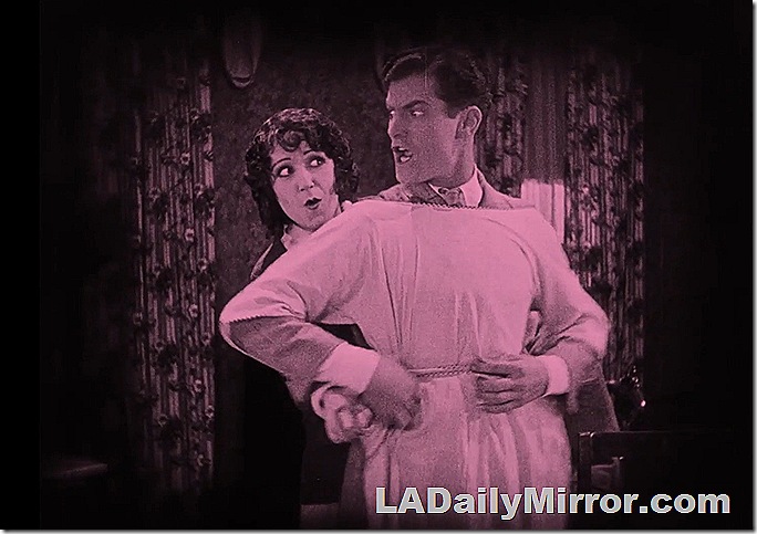 Woman helping man put on an apron. He is displeased. Woman helping man put on an apron. He is displeased.